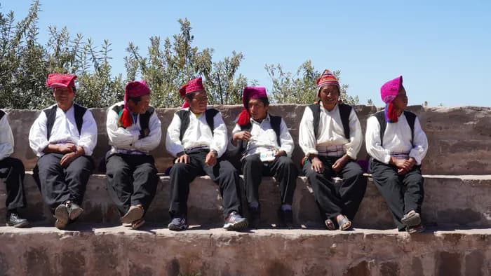 Men of Taquile in their traditional red hats sitting on a stone wall