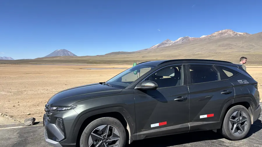 Private vehicle on the altiplano with snow-capped volcanoes behind